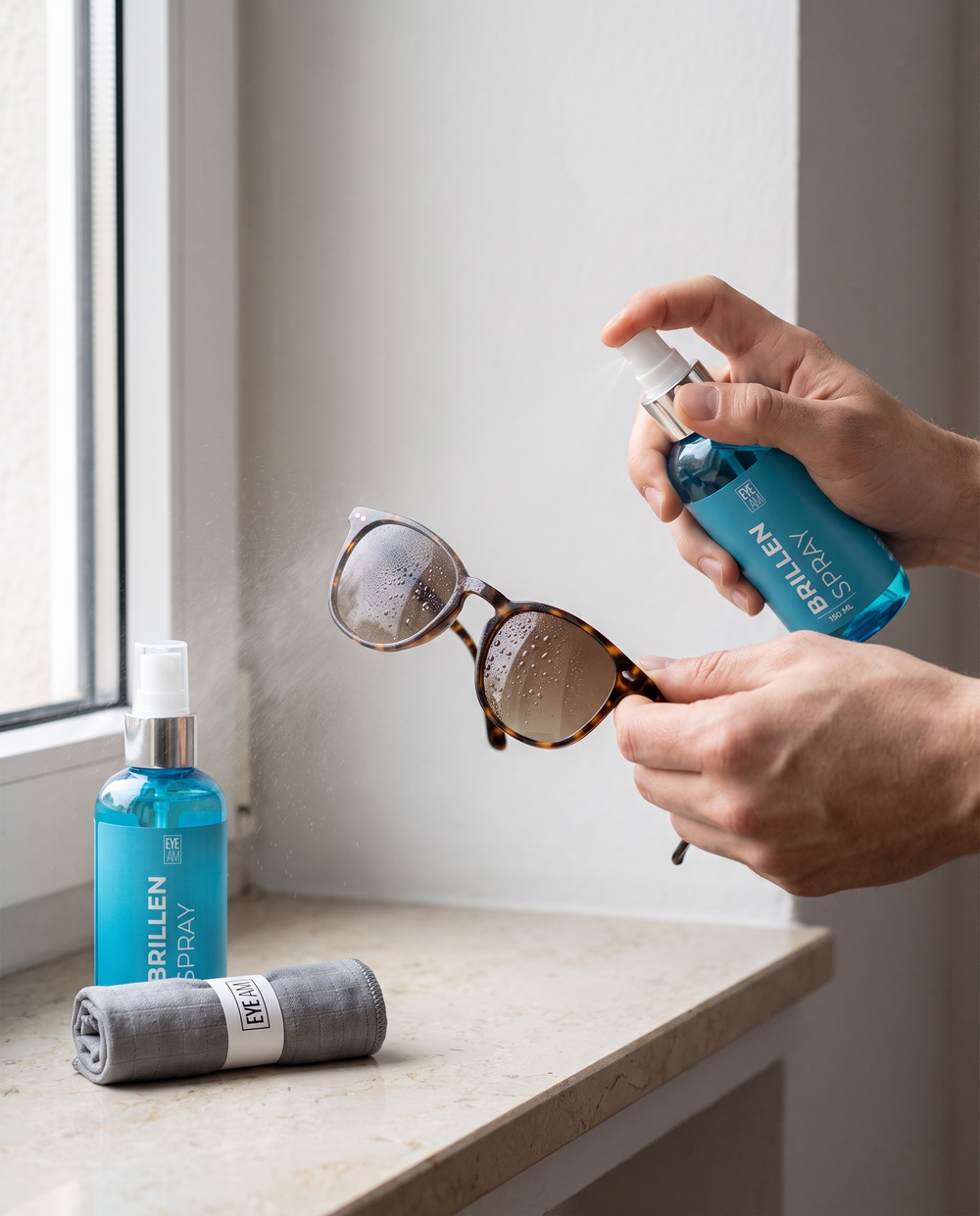 EyeAm Brillenspray auf die Gläser einer Sonnenbrille sprühen